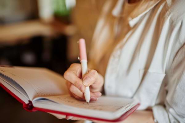 Une femme sérieuse écrit dans un agenda.