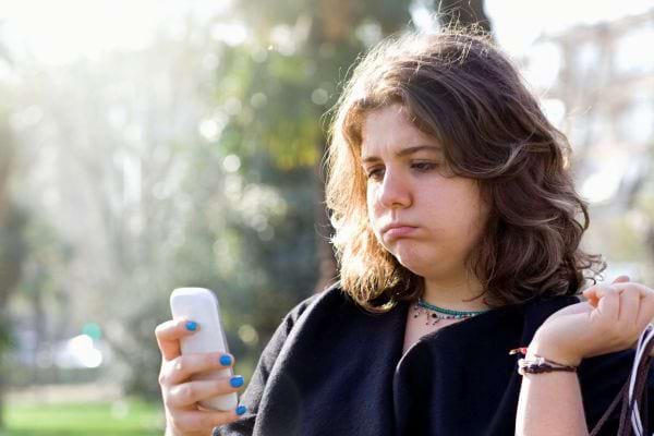 Une femme déçue regarde son smartphone.