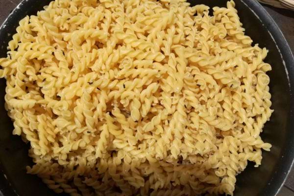 Fusillis jaunes cuits amassés dans une casserole.