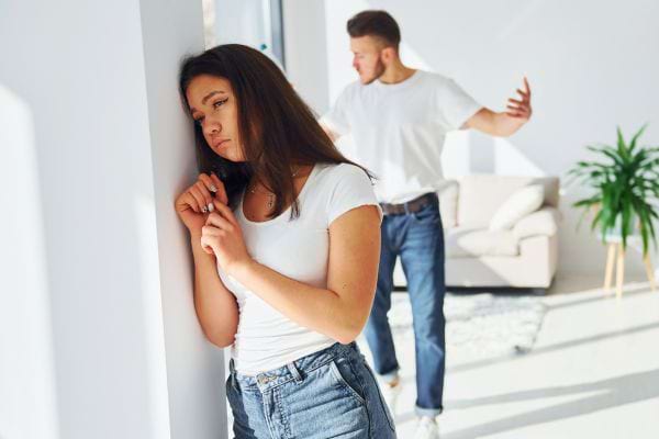 Une femme triste tandis qu'un homme derrière elle crie.