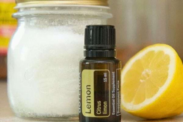 Pot de bicarbonate, huile essentielle de citron et un citron coupé.