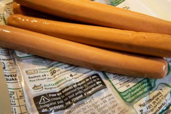 Saucisses Knacki avec emballage partiellement ouvert sur une table.