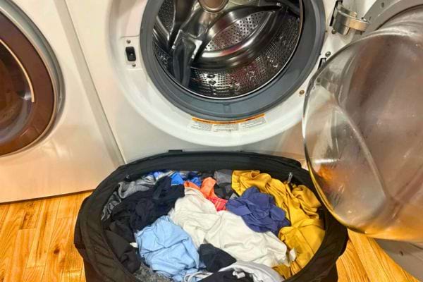 Panier rempli de vêtements devant une machine ouverte.