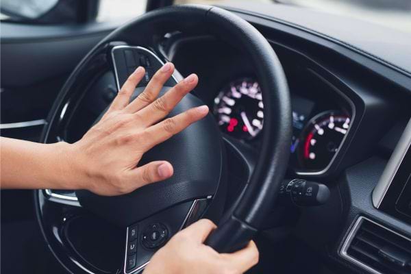 Main contrôlant un volant de voiture.