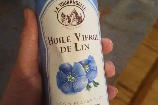 Bouteille d'huile de lin tenue dans une main.