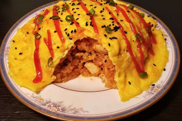 Omelette de riz couverte de sauce et d'oignons verts.