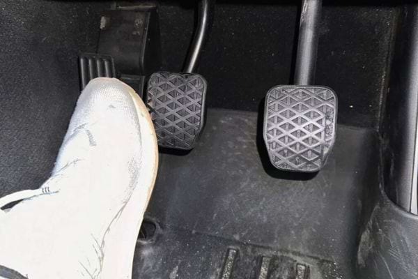 Pied sur la pédale de frein d'une voiture.