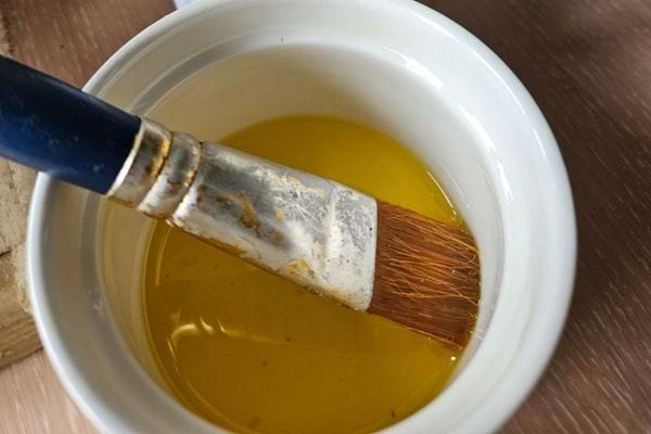 Pinceau trempant dans de l'huile de lin.