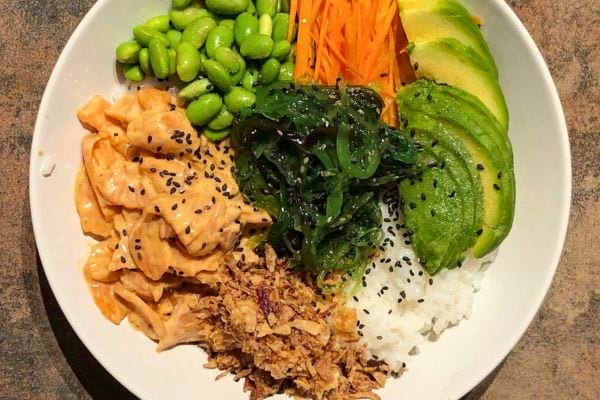 Poke bowl coloré avec riz, saumon, et avocat.