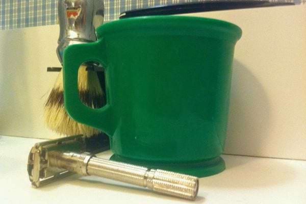 Rasoir et brosse à raser dans un mug vert.