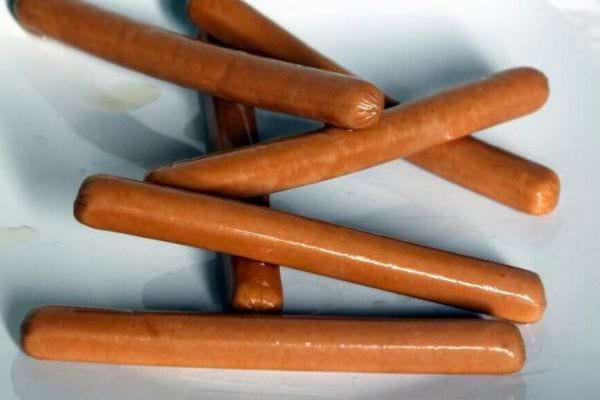 Plusieurs saucisses Knacki disposées sur un plateau blanc.