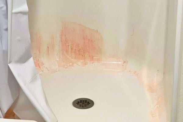 Receveur de douche blanc avec des traces roses sur le fond et les bords.