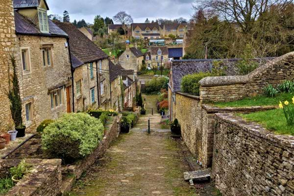 Un vieux village avec des maisons en pierre et un chemin pavé en descente.