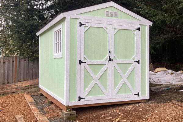 Abri vert clair et blanc au style grange surélevé.