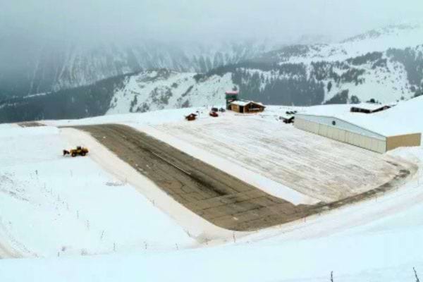 Aéroport en pente au milieu des montagnes enneigées.