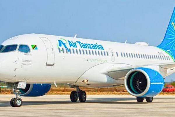 Avion blanc Air Tanzania avec turbine bleue, garé sur le tarmac en plein jour.