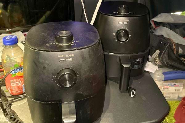 Deux airfryers classiques posés sur une table encombrée.
