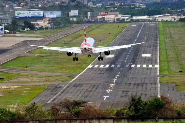 Avion frôlant le sol sur une piste urbaine à flanc de colline.