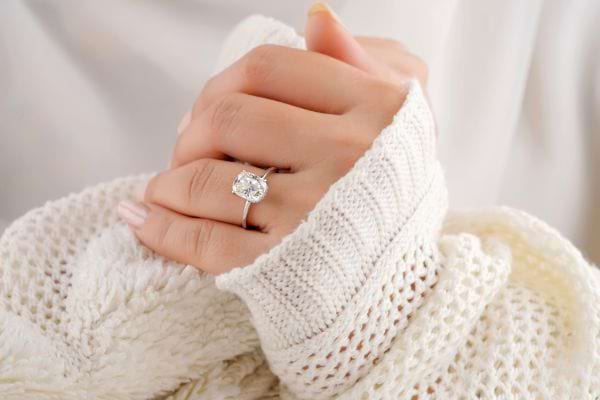 Mains croisées en douceur avec une bague argentée sertie d’un gros diamant.