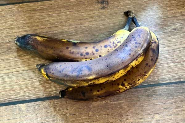Trois bananes mûres avec de nombreuses taches noires.
