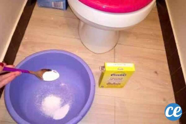 Cuillère de bicarbonate au-dessus d'une bassine devant des toilettes.