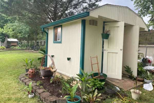 Cabanon crème et turquoise avec plantes en pots autour.