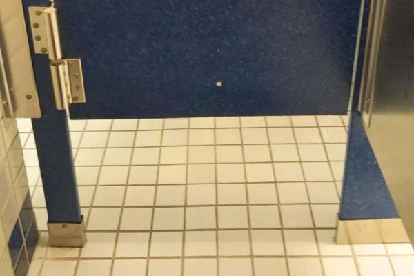 Cabine WC avec porte surélevée et carrelage blanc.