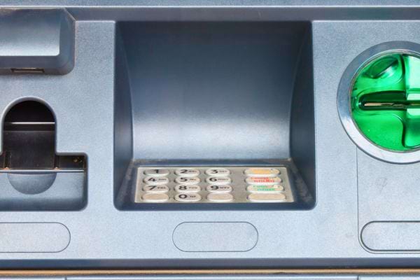 Clavier, fente et lecteur vert d’un distributeur vu en gros plan.