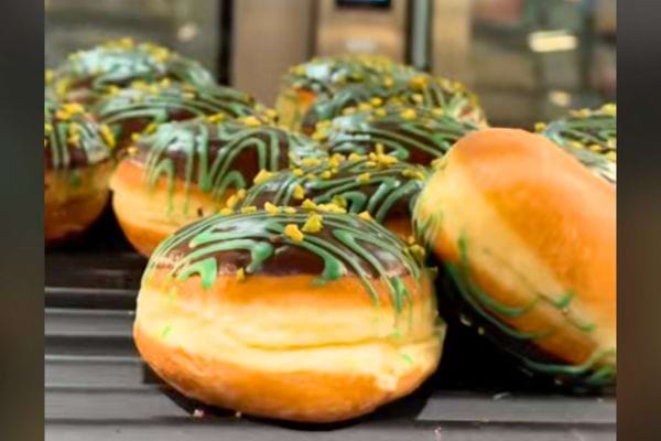 Des donuts verts avec un glaçage au chocolat exposés en vitrine.