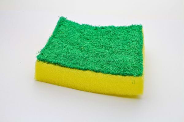 Éponge jaune et verte posée sur fond blanc.