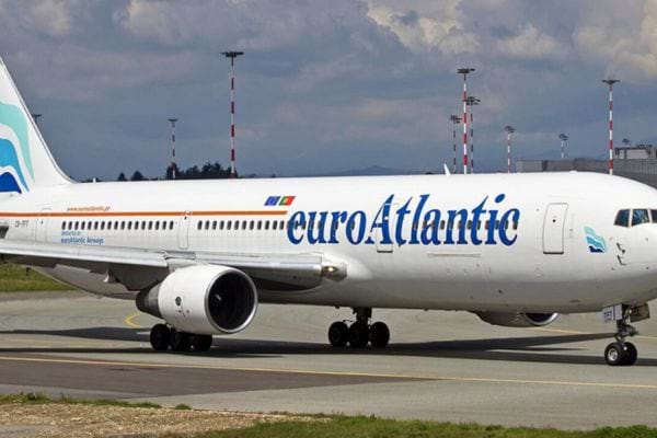 Avion EuroAtlantic blanc et bleu sur une piste avec ciel nuageux.
