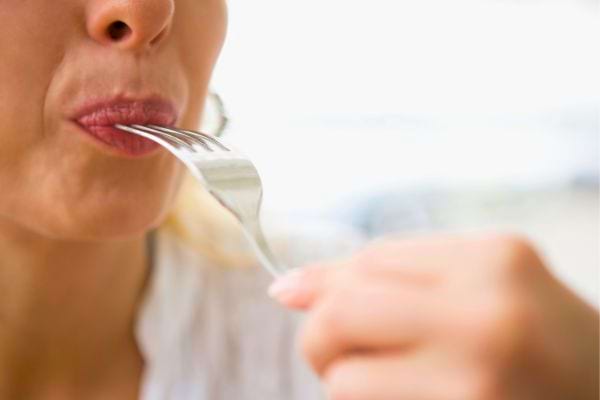 Femme mangeant lentement avec une fourchette.