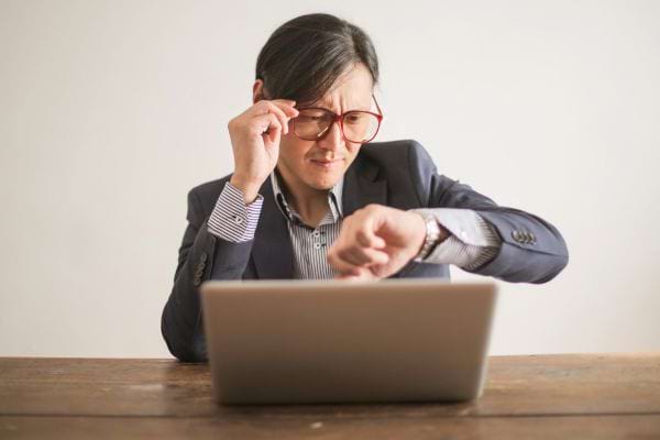 Homme regardant l’heure devant un ordinateur.