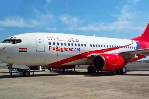 Avion Fly Baghdad blanc et rouge avec drapeau irakien, sur le tarmac.