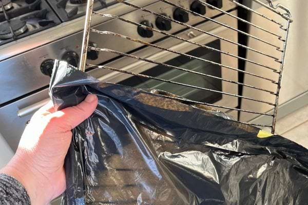 Une grille de four sale est glissée dans un sac poubelle noir.
