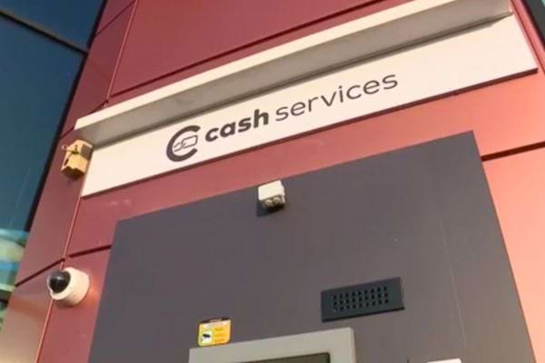 Guichet automatique sous l’enseigne « cash services », avec caméras de surveillance.