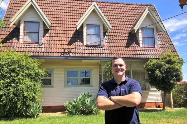 Homme fier devant une maison achetée.