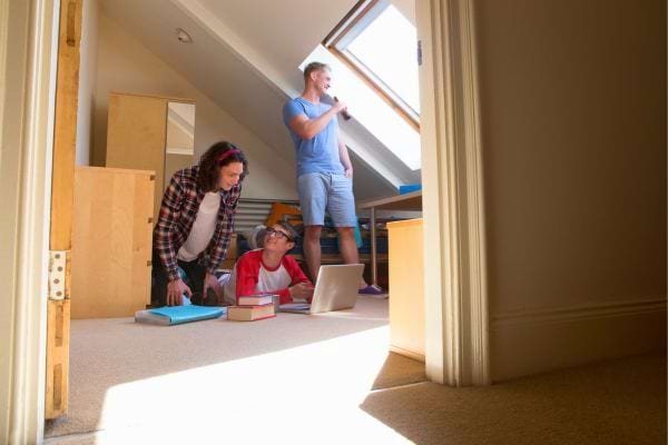 Trois jeunes discutent dans une chambre mansardée.