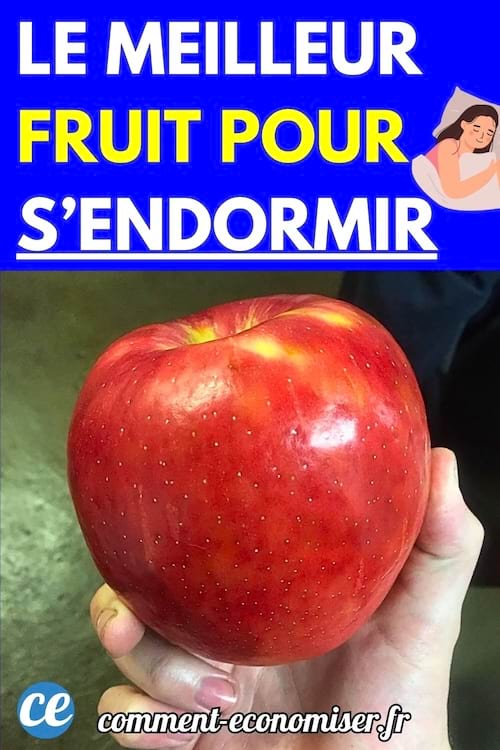 Main tenant une grosse pomme rouge brillante en gros plan.