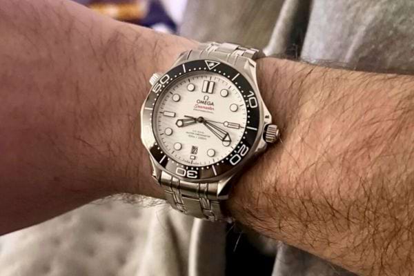 Montre Omega blanche et noire au poignet droit.