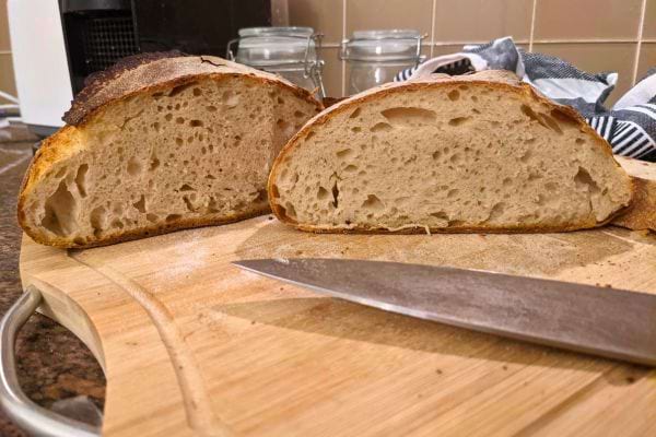 Pain au levain coupé en deux sur planche en bois.