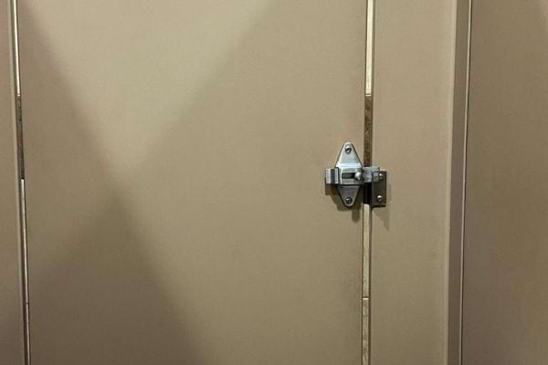 Porte de toilette fermée mais avec un grand jour visible.