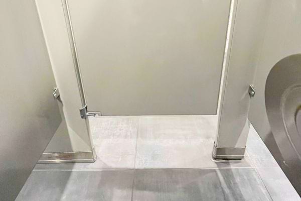 Porte de toilette suspendue laissant un large espace au sol.