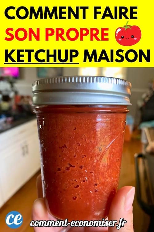 Un pot en verre rempli de ketchup fait maison, tenu en main dans une cuisine.