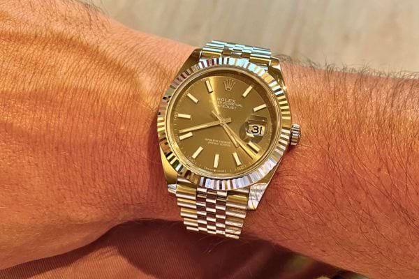 Rolex dorée au poignet avec cadran assorti.