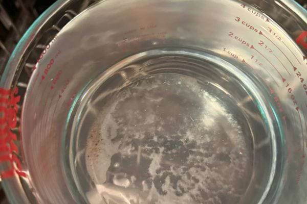 Un verre doseur rempli d’eau chaude.