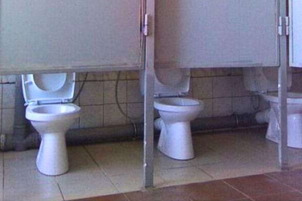 Toilettes côte à côte sans séparation complète.