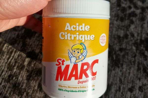 Pot d’acide citrique St Marc tenu à la main.