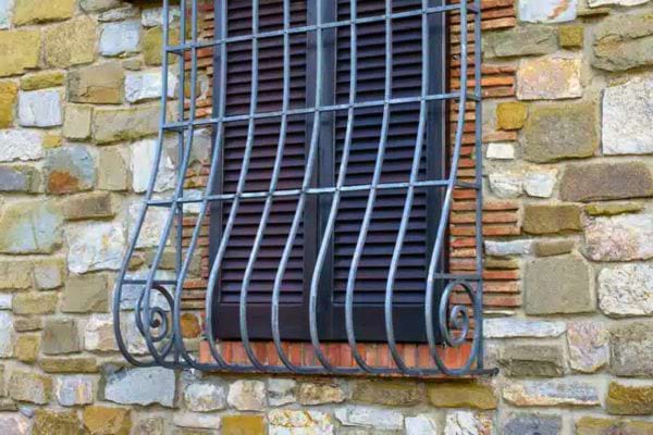 Grille incurvée en fer sur mur en pierre rustique.