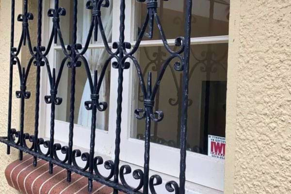 Barreaux travaillés avec motifs en spirale sur façade beige.